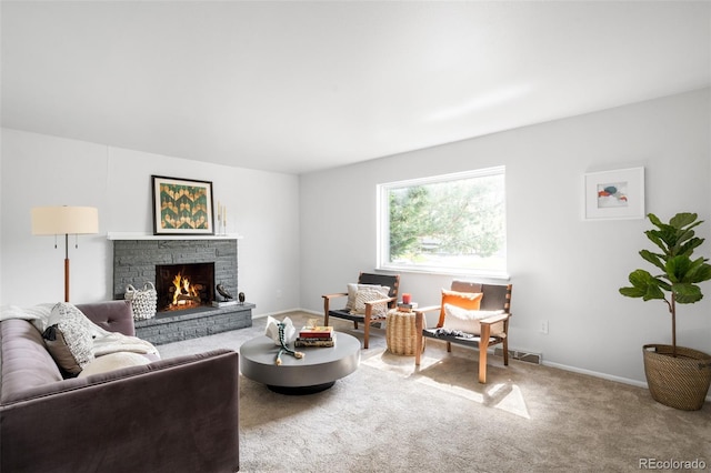 carpeted living room featuring a stone fireplace and baseboards