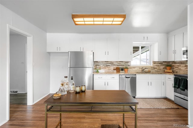 kitchen with stainless steel appliances, a sink, backsplash, white cabinets, and light stone counters