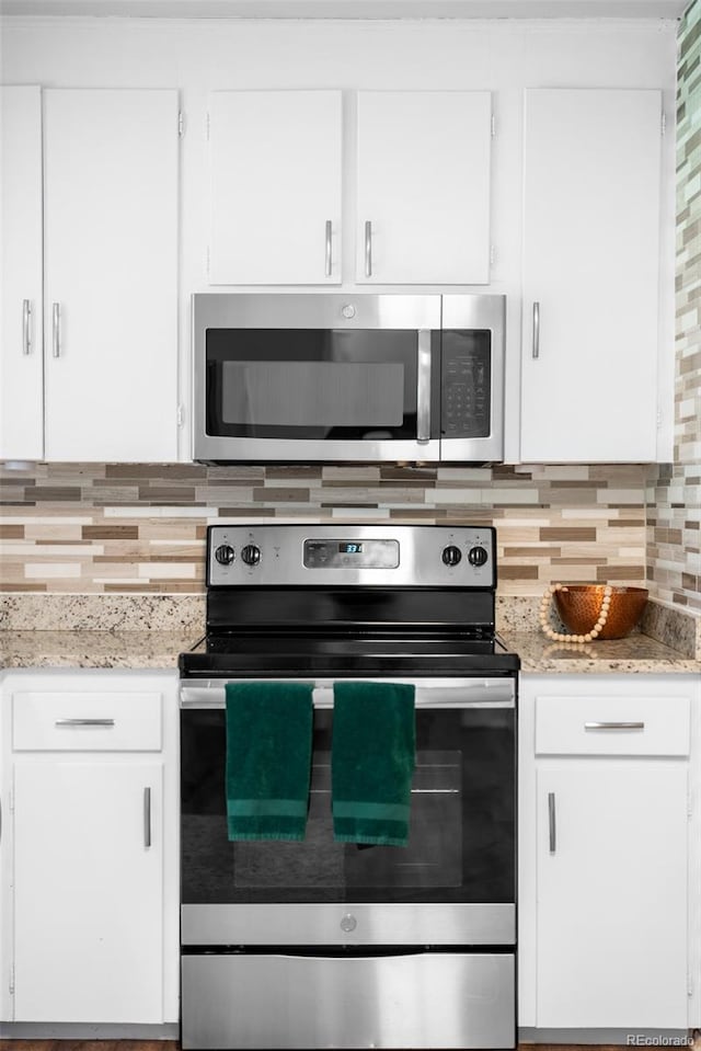 kitchen featuring appliances with stainless steel finishes, tasteful backsplash, white cabinets, and light stone counters