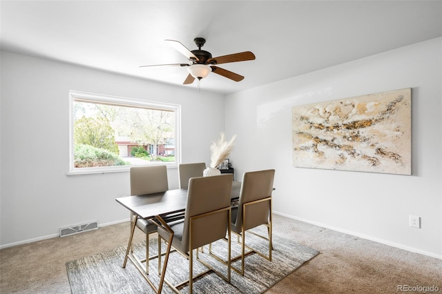 carpeted dining area with a ceiling fan and baseboards