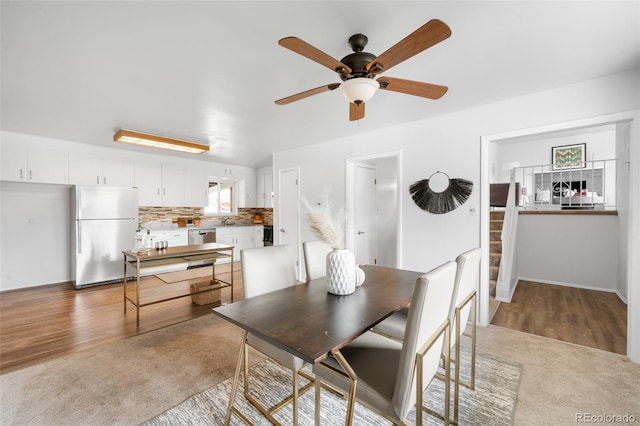 dining area with light carpet, ceiling fan, and light wood finished floors