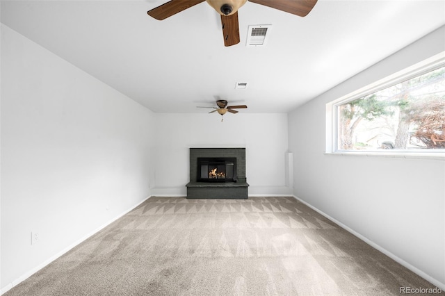 unfurnished living room featuring a ceiling fan, light colored carpet, a brick fireplace, and baseboards