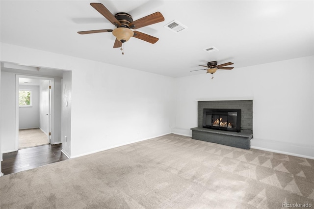 unfurnished living room featuring carpet floors, ceiling fan, a brick fireplace, and baseboards