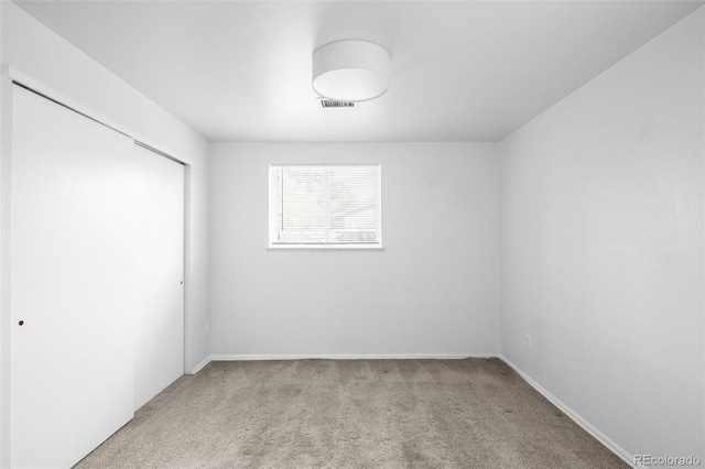 unfurnished bedroom featuring light colored carpet, a closet, and baseboards