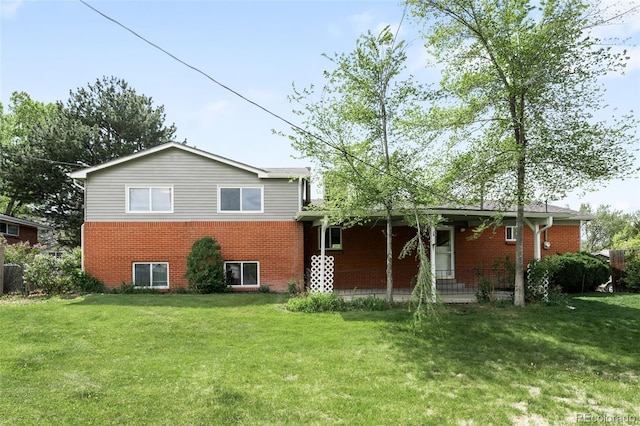 rear view of property with brick siding, a lawn, and covered porch