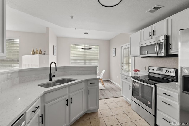 7440 S Blackhawk St Unit 2-108, Englewood, CO 80112 - kitchen with stainless steel appliances, light tile patterned floors, white cabinetry, light stone counters, and hanging light fixtures