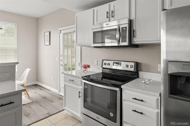 7440 S Blackhawk St Unit 2-108, Englewood, CO 80112 - kitchen featuring appliances with stainless steel finishes, light stone counters, white cabinets, and light tile patterned floors