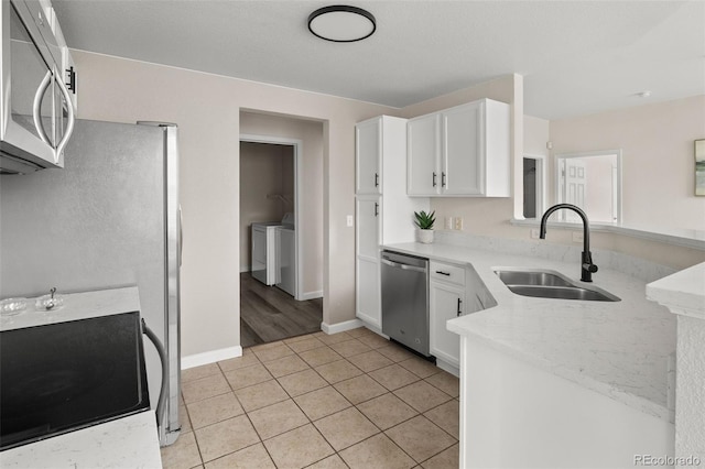 7440 S Blackhawk St Unit 2-108, Englewood, CO 80112 - kitchen featuring appliances with stainless steel finishes, a peninsula, white cabinets, light tile patterned flooring, and light stone countertops