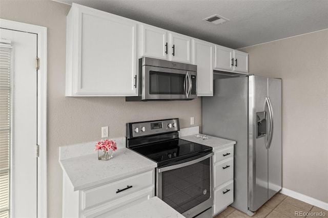 7440 S Blackhawk St Unit 2-108, Englewood, CO 80112 - kitchen featuring stainless steel appliances, white cabinets, light tile patterned floors, and light stone counters