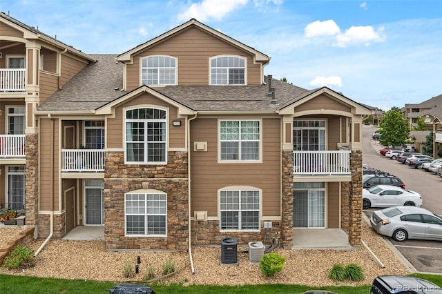 7440 S Blackhawk St Unit 2-108, Englewood, CO 80112 - view of front of home with stone siding, uncovered parking, and a shingled roof