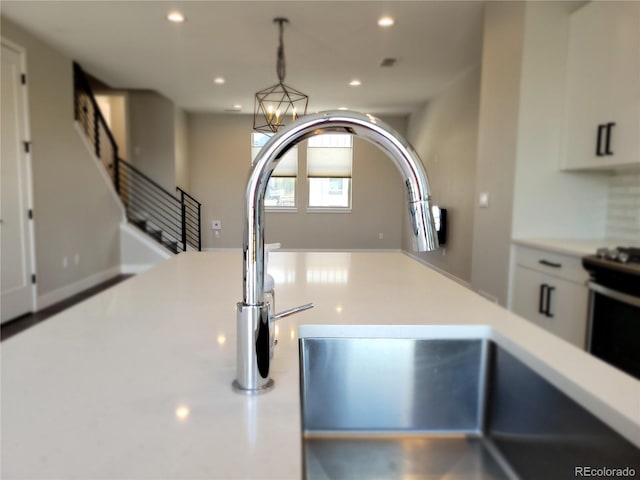 interior details featuring sink, an inviting chandelier, hanging light fixtures, electric range, and white cabinets