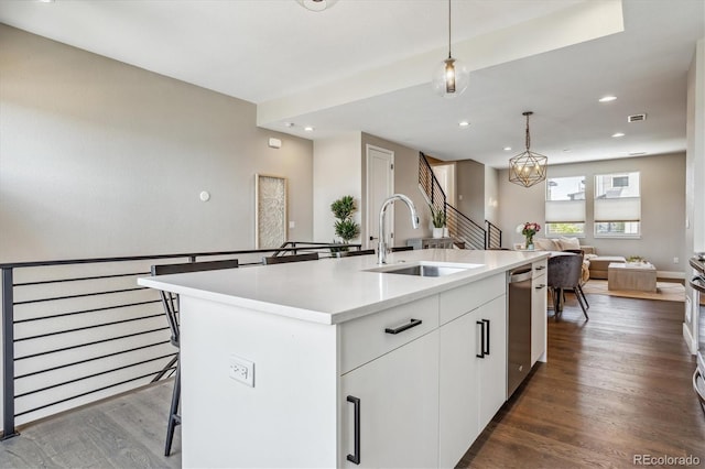 kitchen featuring decorative light fixtures, dishwasher, sink, white cabinets, and a kitchen island with sink