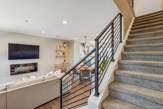 stairway with hardwood / wood-style floors and a notable chandelier