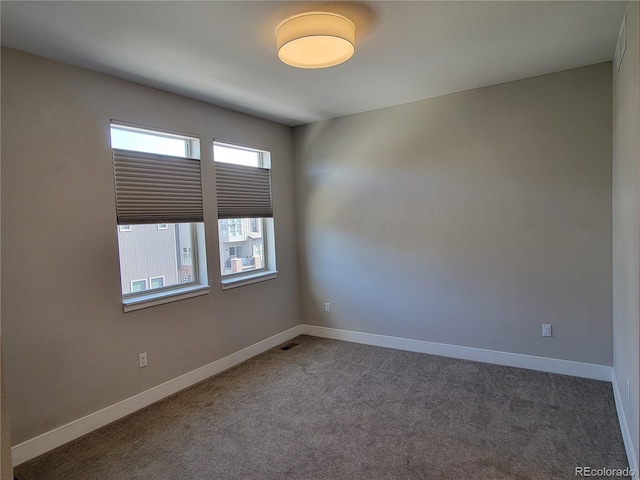 spare room featuring dark colored carpet