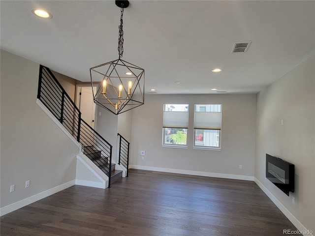 unfurnished living room with dark hardwood / wood-style flooring and a chandelier