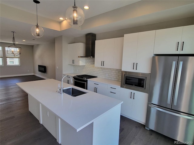 kitchen with stainless steel appliances, white cabinetry, a kitchen island with sink, and wall chimney range hood