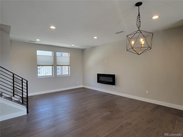 unfurnished living room with a notable chandelier and dark hardwood / wood-style floors