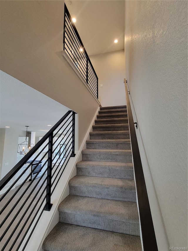 stairs with carpet and a chandelier