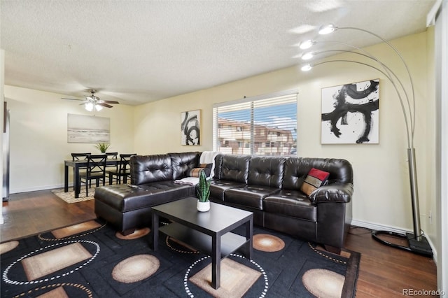 living room with ceiling fan, dark hardwood / wood-style floors, and a textured ceiling