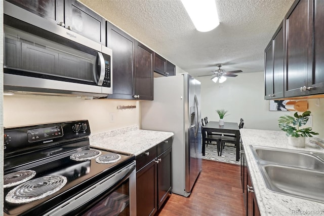 kitchen with sink, dark wood-type flooring, ceiling fan, stainless steel appliances, and dark brown cabinets