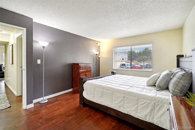 bedroom with dark hardwood / wood-style floors and a textured ceiling