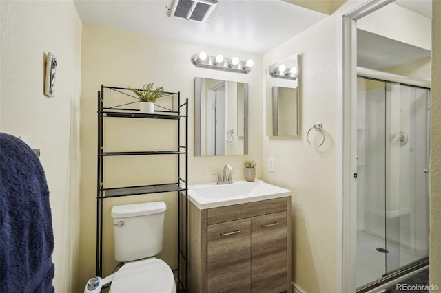 bathroom with vanity, a textured ceiling, a shower with door, and toilet