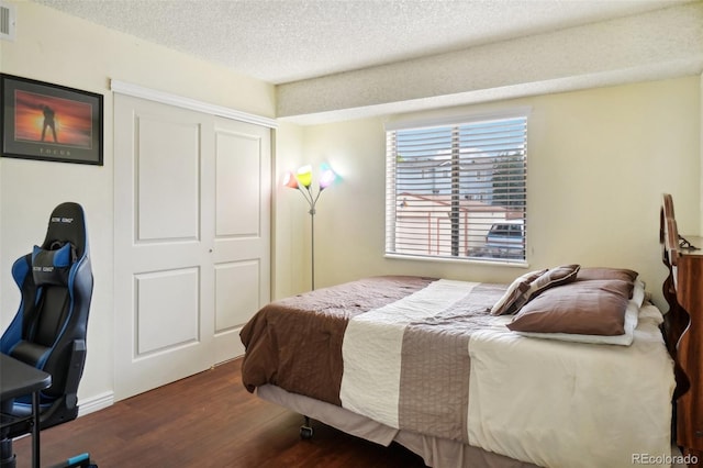 bedroom featuring dark hardwood / wood-style flooring, a closet, and a textured ceiling