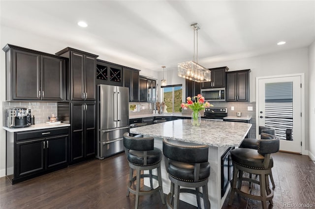 2999 Merry Rest Way, Castle Rock, CO 80109 - kitchen featuring appliances with stainless steel finishes, decorative backsplash, a kitchen island, a breakfast bar area, and recessed lighting