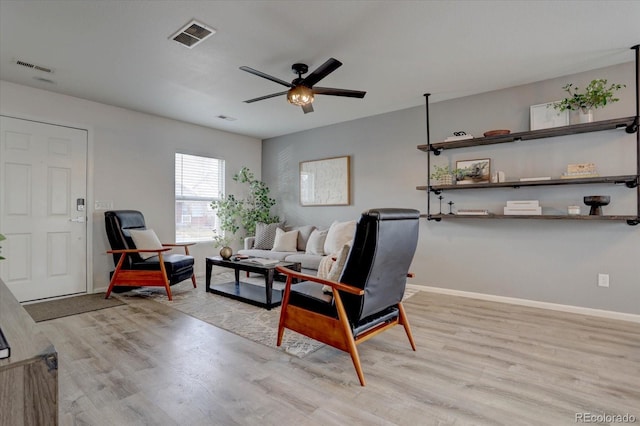 sitting room with a ceiling fan, baseboards, visible vents, and light wood-type flooring