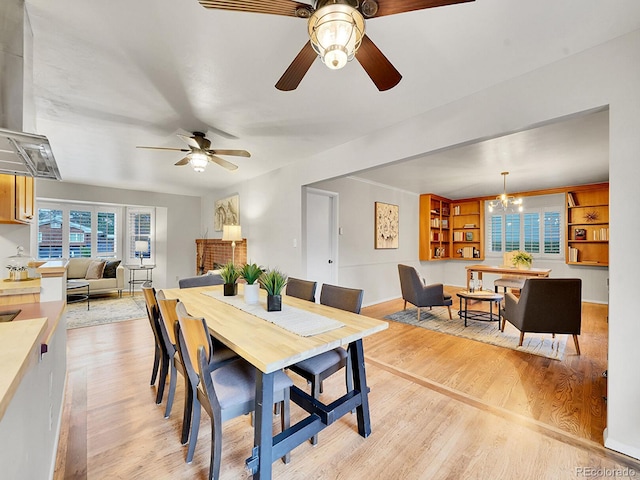 dining space featuring ceiling fan with notable chandelier and light hardwood / wood-style floors