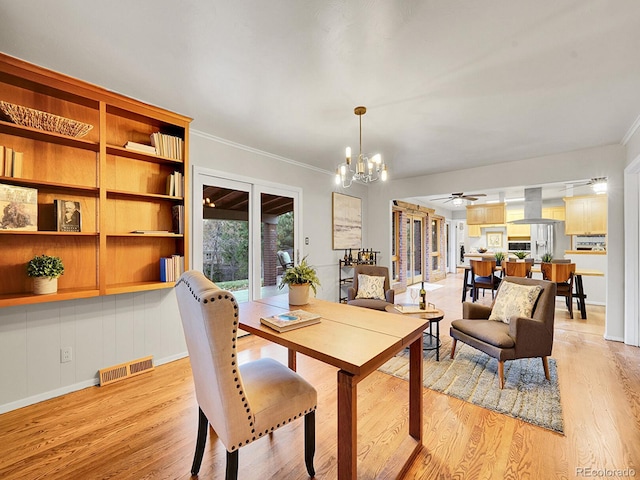 dining area with ceiling fan with notable chandelier, light wood-type flooring, and crown molding