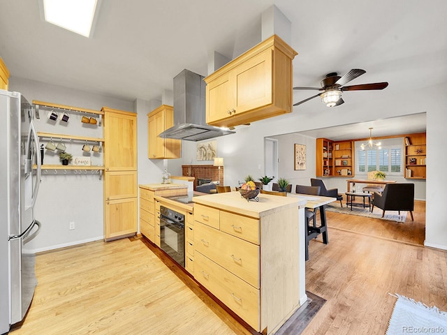 kitchen with light hardwood / wood-style flooring, range hood, stainless steel fridge, black oven, and light brown cabinetry