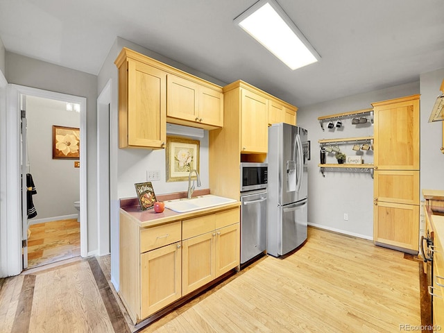 kitchen with appliances with stainless steel finishes, light hardwood / wood-style flooring, light brown cabinetry, and sink