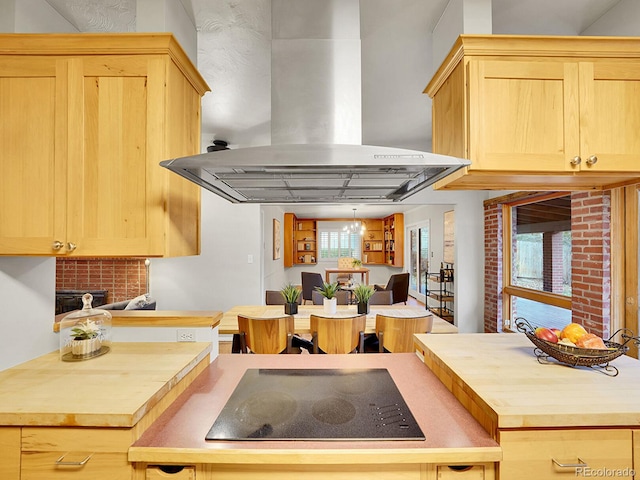 kitchen with black electric stovetop, wall chimney range hood, light brown cabinets, a notable chandelier, and butcher block counters