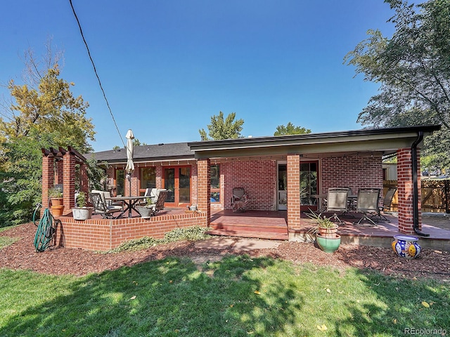 rear view of house with a lawn, a deck, and a patio