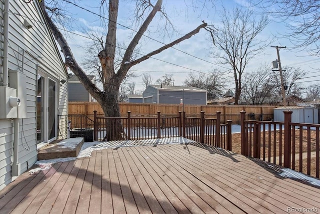 deck with a shed, an outdoor structure, and a fenced backyard