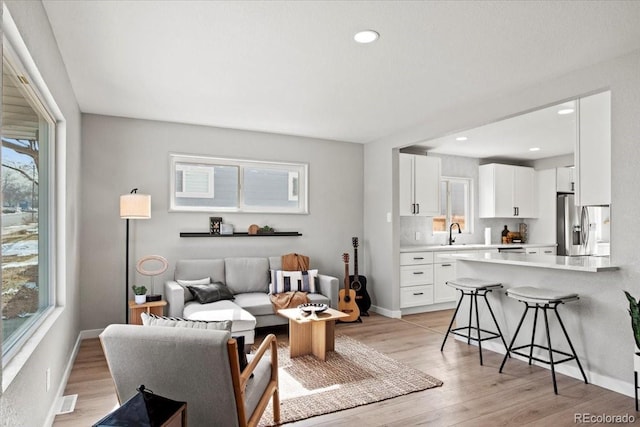 living room with a healthy amount of sunlight, light wood-style flooring, and baseboards