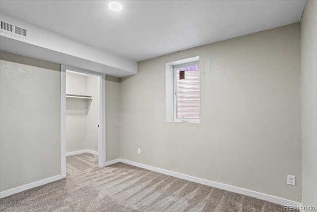 unfurnished bedroom with a walk in closet, carpet flooring, visible vents, and baseboards