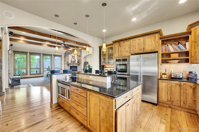 6349 Southridge Greens Blvd, Fort Collins, CO 80525 - kitchen with built in appliances, beam ceiling, light wood-type flooring, open floor plan, and a stone fireplace