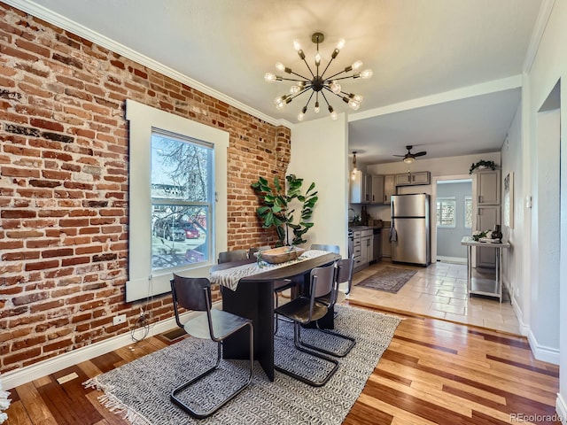 dining room with ornamental molding, plenty of natural light, brick wall, and light hardwood / wood-style flooring