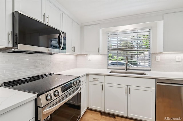 2881 W Long Dr Unit F, Littleton, CO 80120 - kitchen featuring appliances with stainless steel finishes, backsplash, white cabinets, and ornamental molding