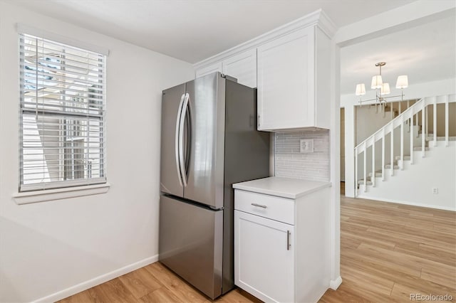 2881 W Long Dr Unit F, Littleton, CO 80120 - kitchen featuring freestanding refrigerator, light wood-style floors, light countertops, white cabinetry, and backsplash