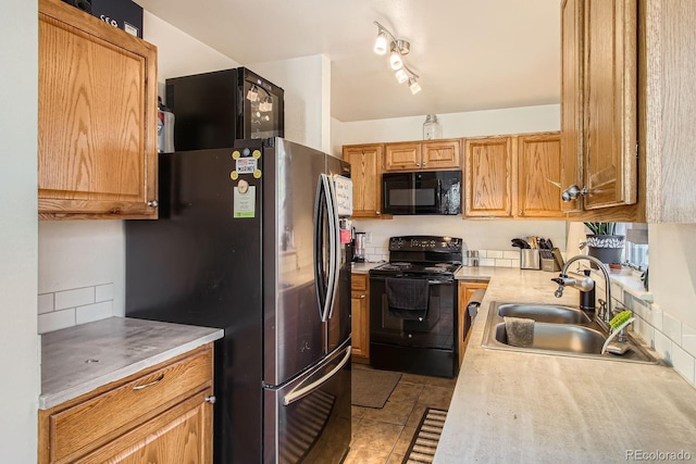 kitchen featuring light countertops, light tile patterned floors, a sink, and black appliances