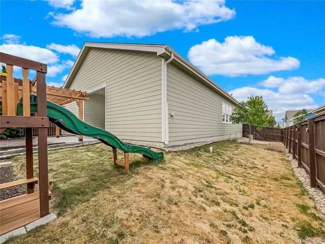 view of side of home with a yard, a pergola, and a playground