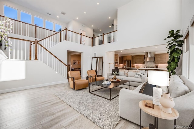 living room featuring recessed lighting, visible vents, light wood-style flooring, and stairs