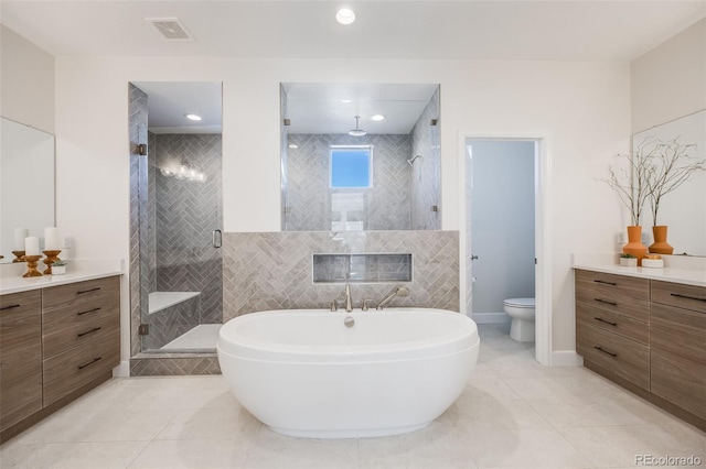 bathroom with visible vents, toilet, a stall shower, vanity, and tile patterned floors