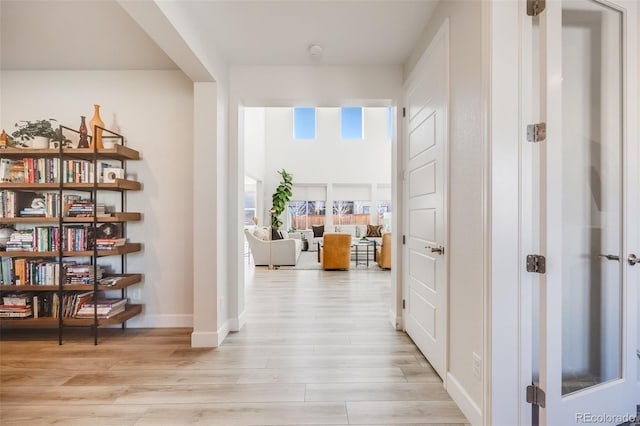 hallway featuring light wood-style flooring and baseboards