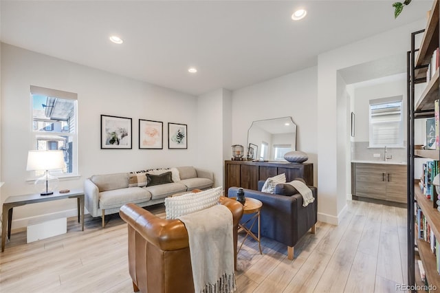 living room featuring recessed lighting, baseboards, a healthy amount of sunlight, and light wood finished floors