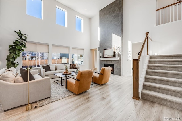 living area featuring a tiled fireplace, stairway, and wood finished floors