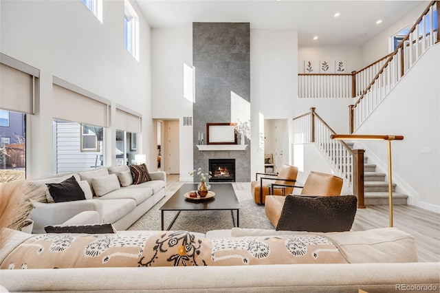 living room with a fireplace, wood finished floors, visible vents, baseboards, and stairs